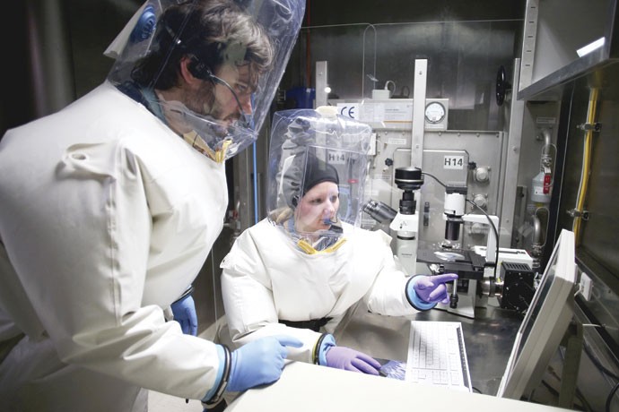 Segurança máxima: Pesquisadores de Hamburgo, na Alemanha, usam traje especial para trabalhar em laboratório onde são manipulados patogênicos capazes de se espalhar entre a população (Foto: Christian Charisius/ DPA/ ZUMAPRESS)