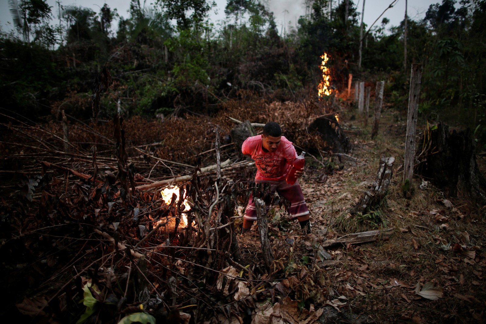 Voluntário acende uma fogueira para criar um aceiro para impedir o progresso de um incêndio iniciado por agricultores que limpam uma área da selva amazônica, em Apuí, no AmazonasREUTERS