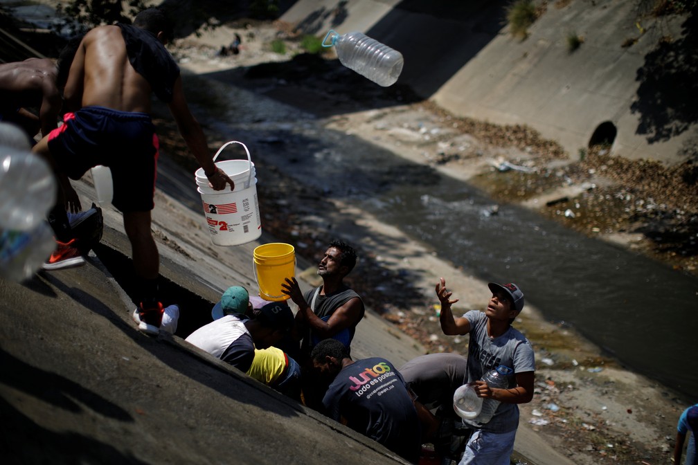 Venezuelanos coletam água de esgoto que corre para o Rio Guaire — Foto: Reuters/Carlos Garcia Rawlins