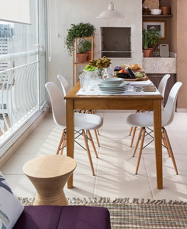 A mesa de madeira clara faz com que os moradores recebam os convidados com muito mais conforto na varandinha! Todos os móveis do espaço são Tok & Stok (Foto: Divulgação)