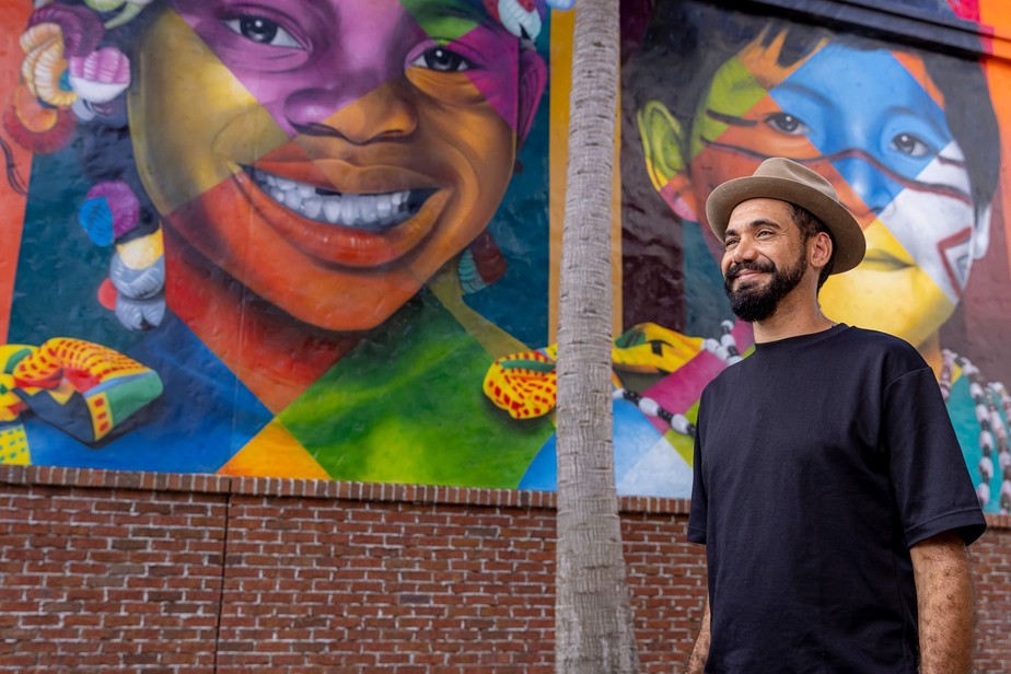 Eduardo Kobra ao lado do mural que pintou no complexo Disney Springs, nos EUA