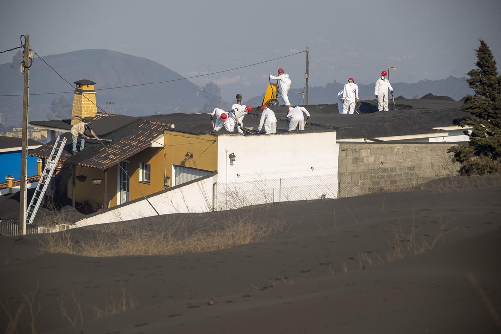 Integrantes da Unidade Militar de Emergência da Espanha usam equipamentos de proteção para limpar as cinzas de telhados em La Palma — Foto: Luismi Ortiz/UME/AFP
