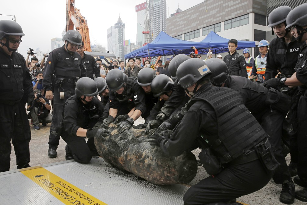 Policiais movem nesta sexta-feira (11) uma bomba desativada descoberta durante obras do metrÃ´ em Hong Komg (Foto: Kin Cheung/ AP Photo)