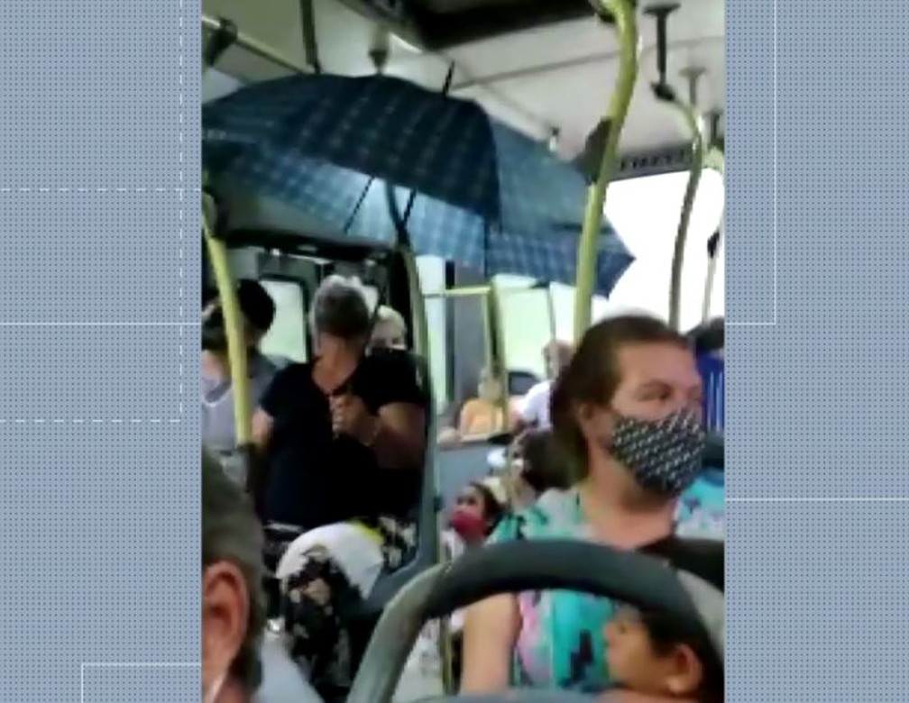 Mulher usa guarda-chuva dentro de ônibus para não se molhar com chuva no veículo, em linha do litoral do Paraná — Foto: Reprodução/RPC