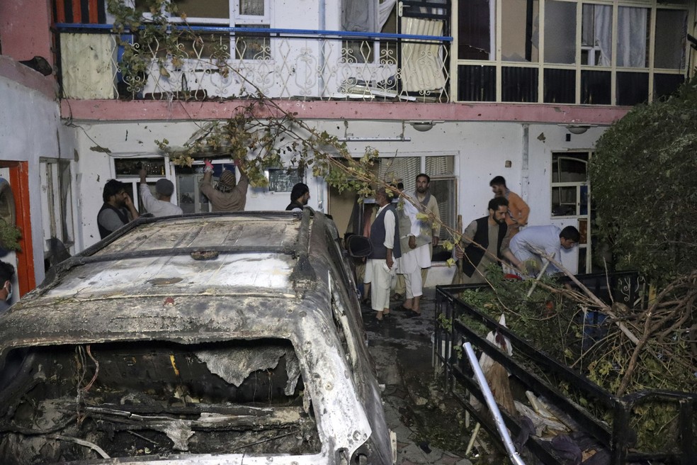 Afegãos em frente a casa atingida após um ataque de drone dos Estados Unidos em Cabul, capital do Afeganistão, em 29 de agosto  — Foto: Khwaja Tawfiq Sediqi/AP