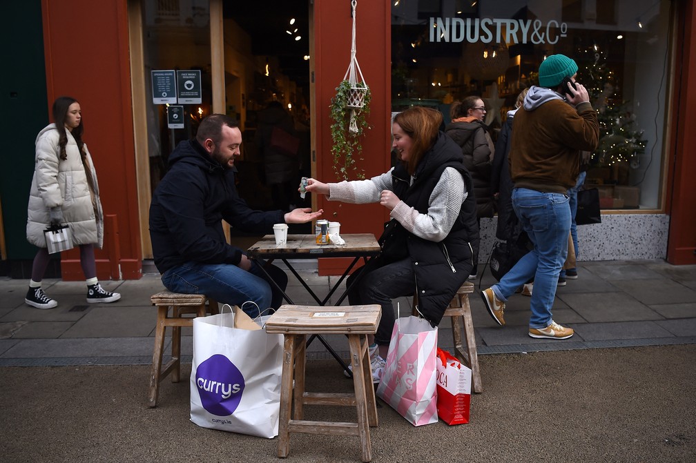 Pessoas higienizam as mãos do lado de fora de comércio em Dublin, Irlanda, em meio a pandemia da Covid-19 em foto de 17 de dezembro de 2021 — Foto: Clodagh Kilcoyne/Reuters