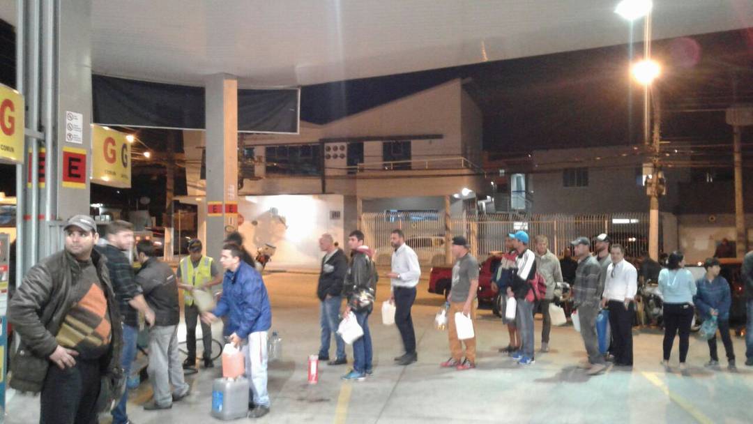 Com galÃµes nas mÃ£os, moradores de FlorianÃ³polis (SC) fazem fila para pegar gasolina em posto de combustÃ­vel. A fila jÃ¡ dobra o quarteirÃ£o