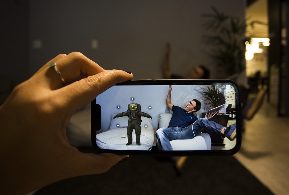 Simulação na tela - CEO da R2U, Caio Jahara, de 29 anos, testa solução de realidade aumentada que permite visualizar produtos como uma cadeira em uma sala Agência O Globo — Foto:         