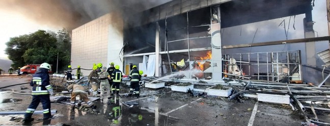 Bombeiros apagam fogo em um shopping atingido por um ataque de mísseis russos na cidade ucraniana de Kremenchuk — Foto: SERVIÇO DE IMPRENSA DO MINISTÉRIO DE EMERGÊNCIA DA UCRÂNIA / AFP