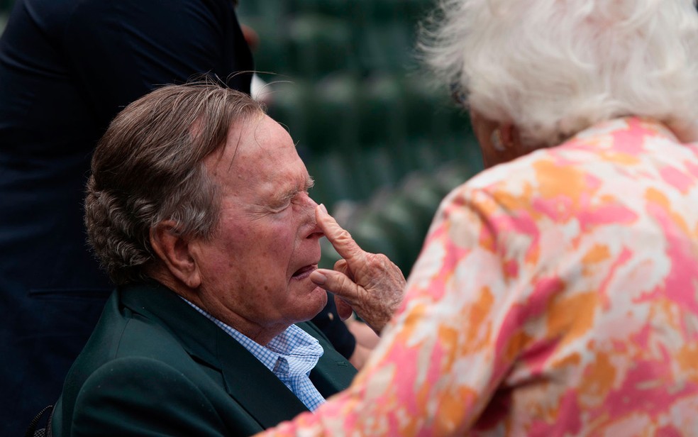A ex-primeira dama dos EUA, Barbara Bush, aplica protetor solar no nariz do ex-presidente, George H.W. Bush, antes de um jogo de beisebol em Houston, Texas, em 3 de maio de 2015 (Foto: AP Photo/George Bridges, File)
