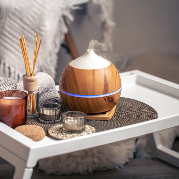 Oil diffuser on blurred background near candles. Aromatherapy and health care concept. (Foto: Getty Images/iStockphoto)