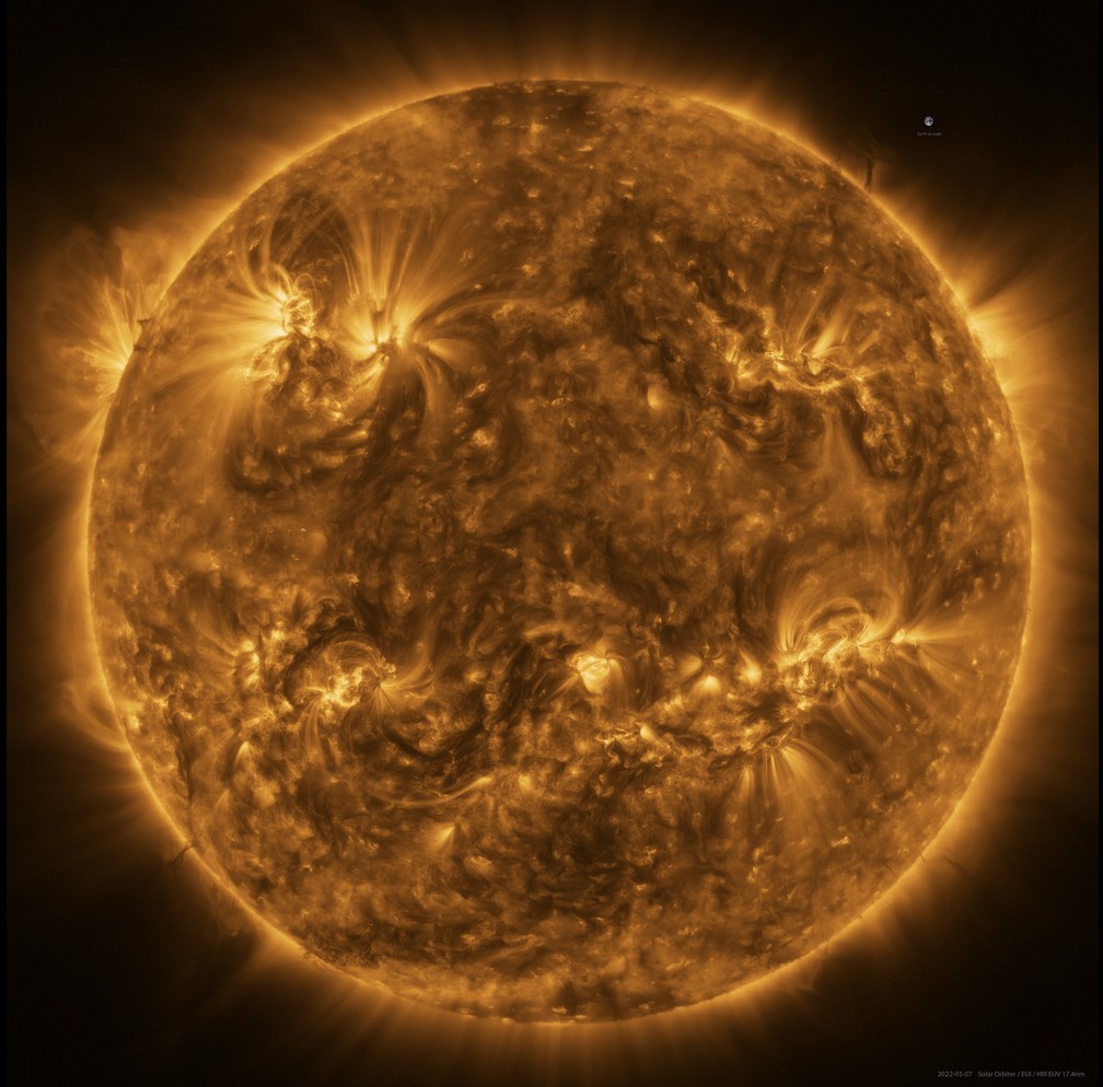 O Sol visto pelo Solar Orbiter em luz ultravioleta extrema a uma distância de aproximadamente 75 milhões de quilômetros. A imagem é um mosaico de 25 imagens individuais tiradas em 7 de março pelo telescópio de alta resolução do instrumento Extreme Ultraviolet Imager (EUI). Ao lado, em cima (posição de 'duas horas' no relógio), é possível ver a Terra, em escala, para comparação. — Foto: ESA & NASA/Solar Orbiter/EUI; Processamento de dados: E. Kraaikamp (ROB)