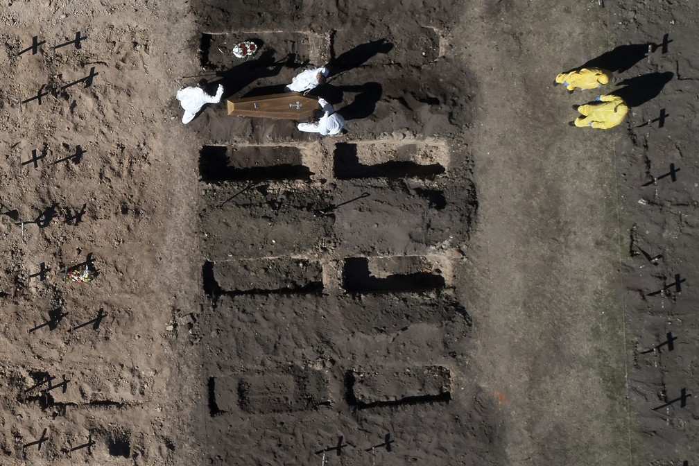 Foto aérea mostra coveiros enterrando um caixão em uma área aberta para acomodar novos túmulos no cemitério de Chacarita, em Buenos Aires, nesta terça-feira (11), e atender à alta demanda durante a pandemia de coronavírus — Foto: Emiliano Lasalvia/AFP