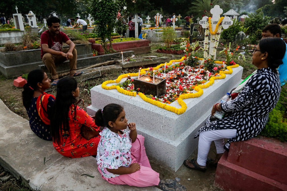 Uma família se reúne para rezar ao redor de um túmulo durante o dia de finados em Calcuta, na Índia, neste sábado (02) — Foto: Bikas Das/AP