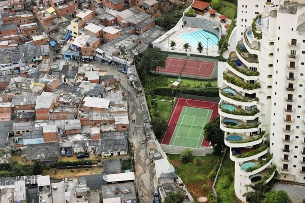 Casas de Paraisópolis e prédio de luxo no Morumbi: separados por um muro, com estatísticas bem diferentes — Foto: Tuca Vieira via BBC