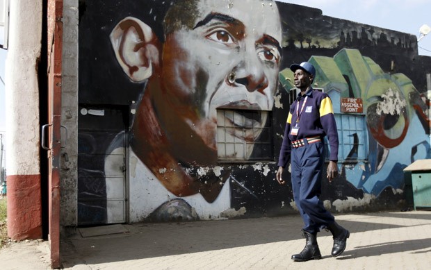 Um segurança passa por um muro com um grafite do presidente dos EUA Barack Obama no centro de Nairobi, capital do Quênia, na sexta-feira (17) (Foto: Thomas Mukoya/Reuters)