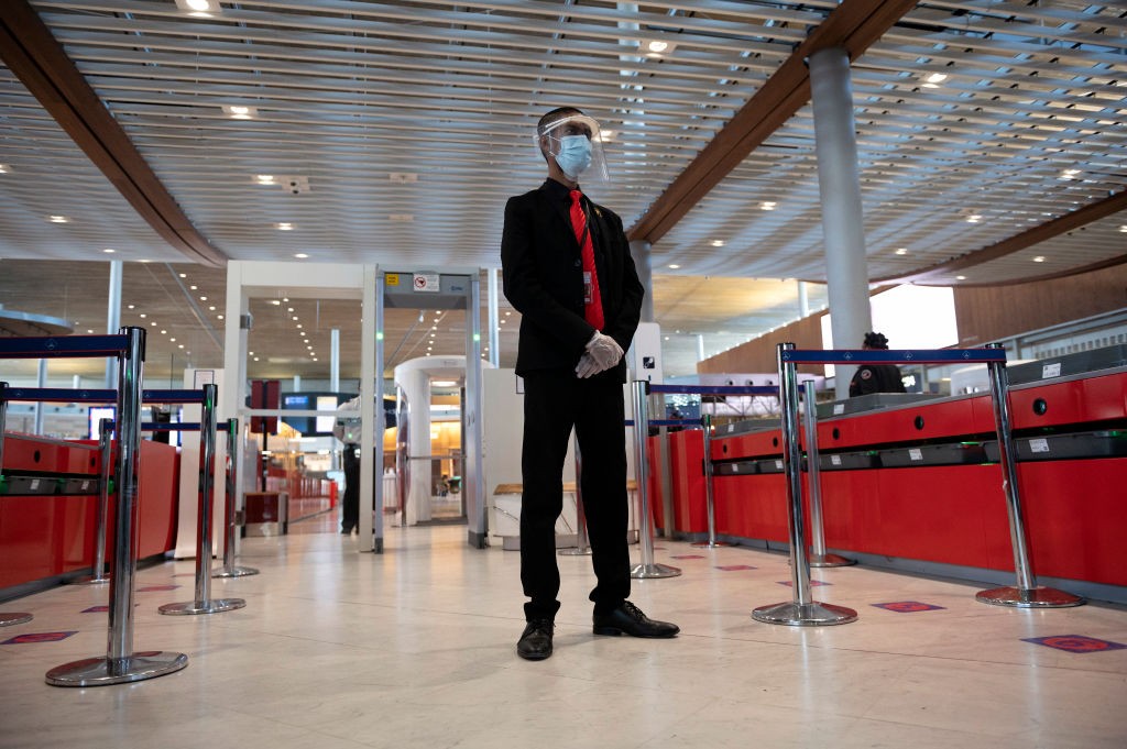 PARIS, FRANCE - MAY 14: An airport security officer wearing a face mask and a plastic shield waits for travelers for security check before boarding at Roissy Charles De Gaulle airport during the Coronavirus (COVID)19) pandemic on May 14, 2020 in Paris, Fr (Foto: Getty Images)