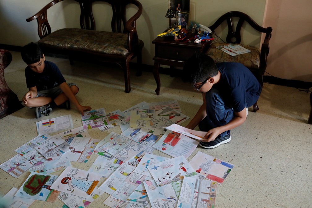 Gabriel Moncada olha para seus desenhos em sua casa em Caracas — Foto: Marco Bello/Reuters