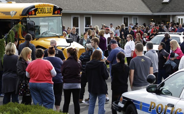 Pais se reúnem em volta de ônibus escolar que tirou parte dos alunos do colégio de Marysville (Foto: AP/Ted Warren)
