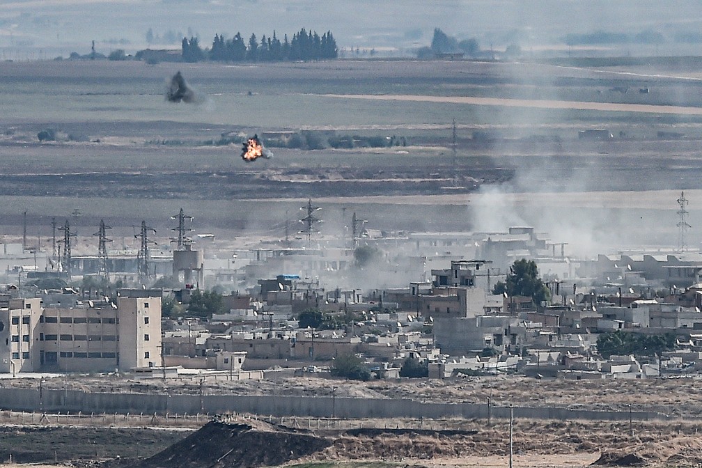 Fumaça é vista na cidade síria de Ras al-Ain, na fronteira com a Turquia, neste domingo (13)  — Foto: Ozan Kose / AFP 