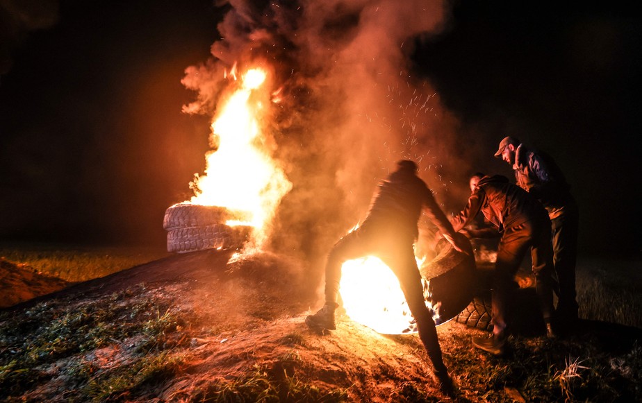 Jovens palestinos queimam pneus durante um protesto perto da fronteira Israel-Gaza, a leste da cidade de Gaza