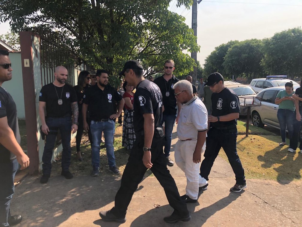Jairo Narciso da Silva (de branco), de 64 anos, chegou escoltado por policiais para acompanhar a escavação dos restos mortais da mulher dele em Sinop — Foto: Poliana Mazzo/TV Centro América