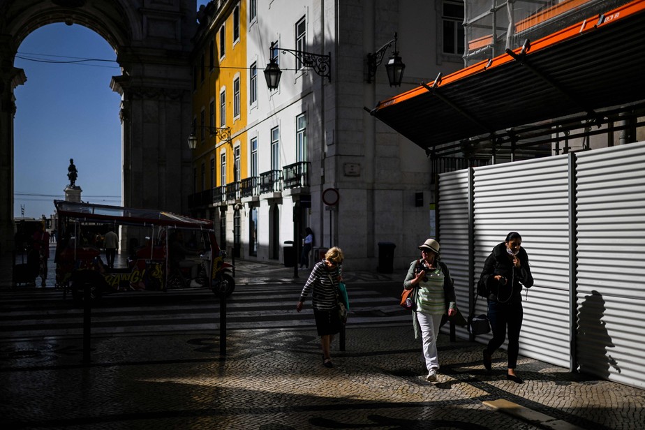 Pedestres caminham junto ao arco da Rua Augusta, em Lisboa