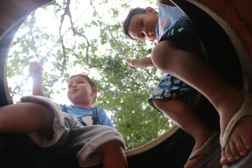 Sobrinho e filho de Kimberly brincam juntos no balanÃ§o improvisado com um pneu â€” Foto: Joyce Heurich/G1