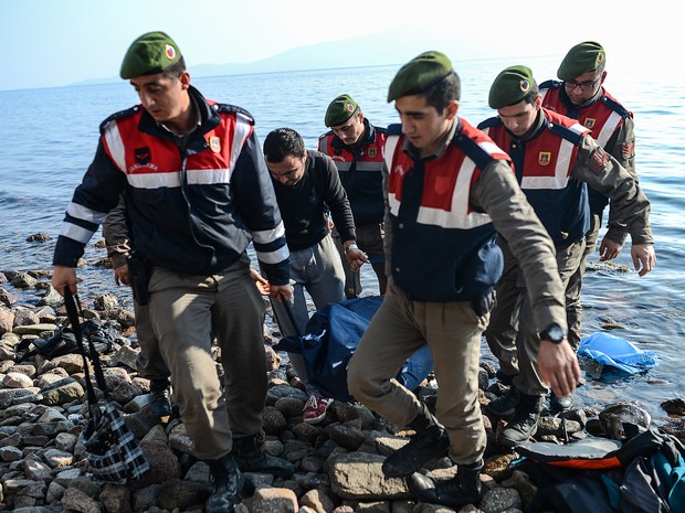 Policiais turcos carregam corpo de migrante morto em naufrágio no Mar Egeu neste sábado (30) (Foto: Ozan Kose/AFP)