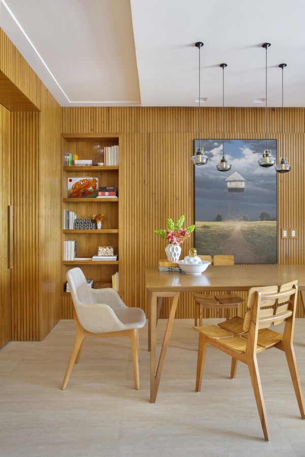 Detalhe da sala de jantar mostra nicho de madeira na parede, onde são expostos livros e enfeites da família 