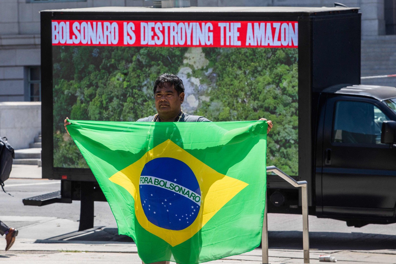 Toya Manchineri durante protesto em Los Angeles, em que segura uma bandeira com os dizeres "Fora, Bolsonaro" — Foto: APU GOMES / AFP