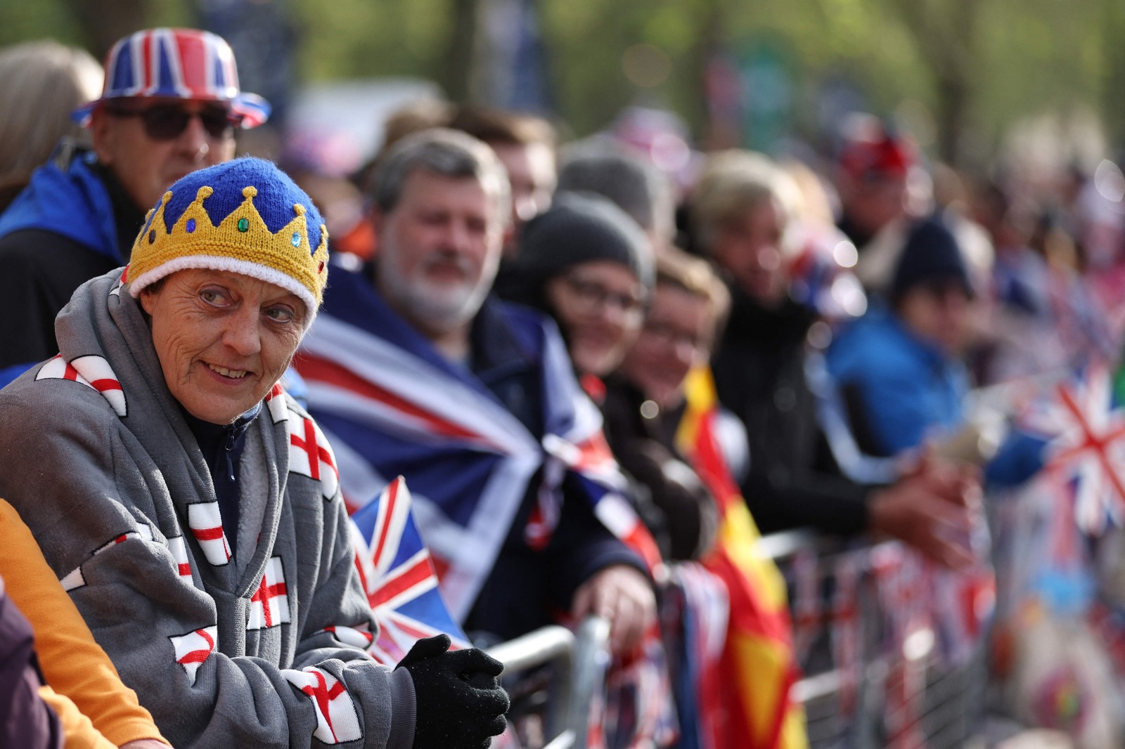Súditos se posicionam na rota da "Procissão do Rei" para assistir à parte da coroação do rei Charles III — Foto: Richard Heathcote / AFP