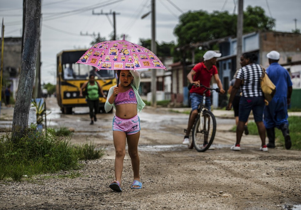 Menina se protege da chuva em Batabano, em Cuba, de onde furacão Ian se aproxima, em 26 de setembro de 2022.  — Foto: Ramon Espinosa/ AP 