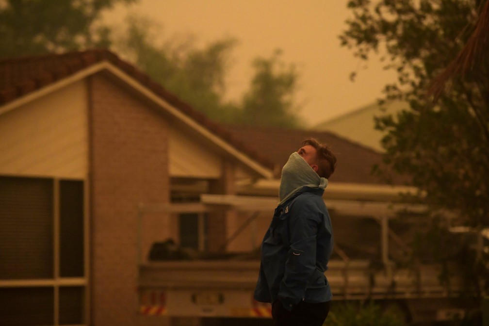 4 de janeiro - Um morador observa a fumaça aparecer trazida junto com cinzas por ventos fortes em direção a Nowra, na Austrália — Foto: Tracey Nearmy/Reuters