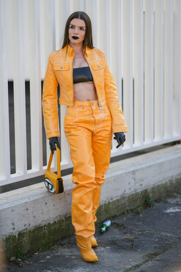 MILAN, ITALY - FEBRUARY 23: Julia Fox wears a black shiny leather shoulder-off / cropped top, an orange shiny varnished leather zipper biker jacket from Diesel, matching orange shiny varnished leather large panties pointed heels shoes, black shiny vinyl g (Foto: Getty Images)