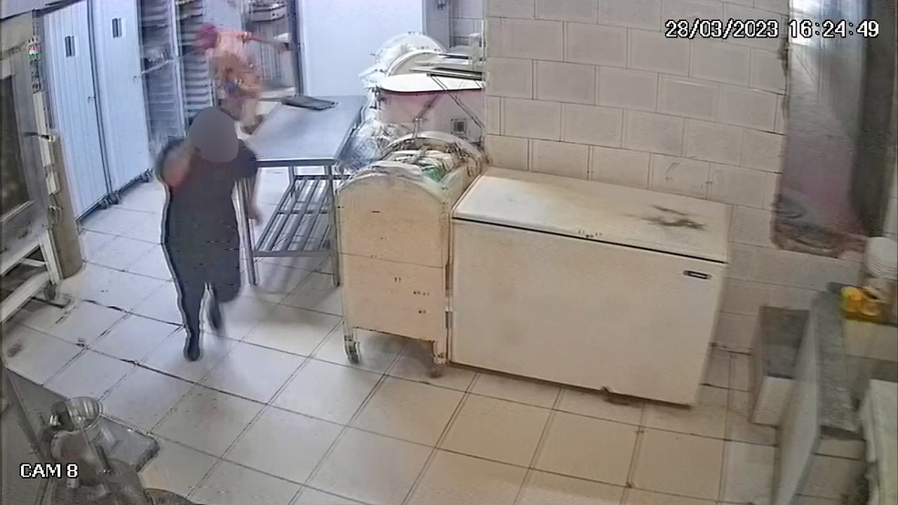 Funcionária tenta se proteger de tiros na cozinha da padaria — Foto: Reprodução/TV Globo