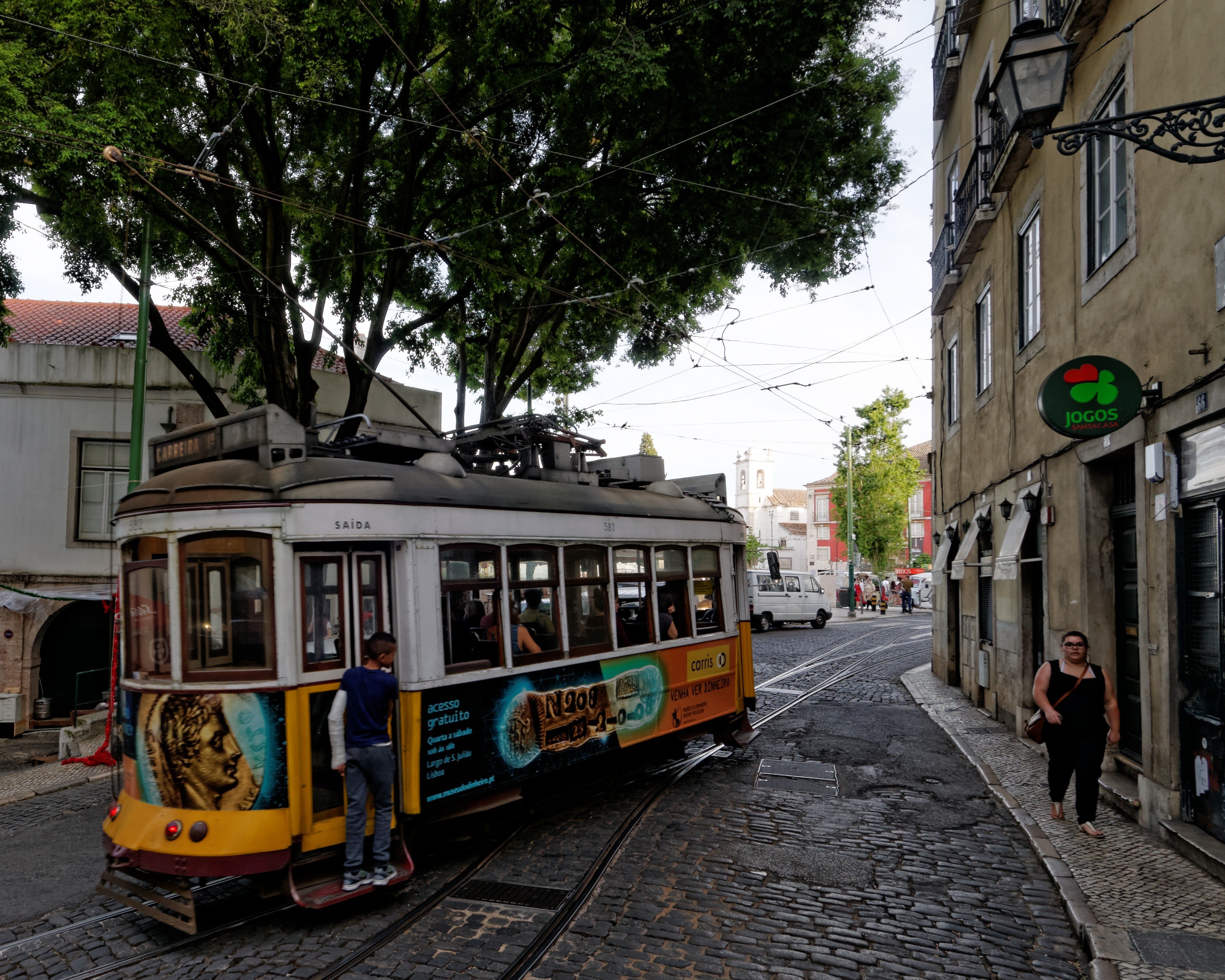 Menino pega carona em um bondinho em Alfama, Lisboa