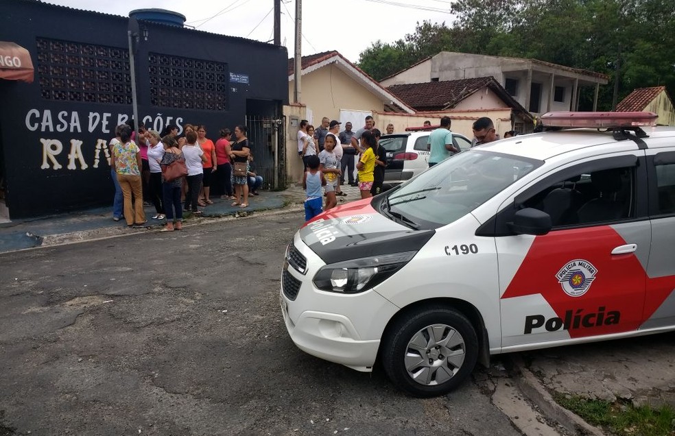 Populares observam a ação da polícia na casa onde viviam os idosos (Foto: Dione Aguiar)