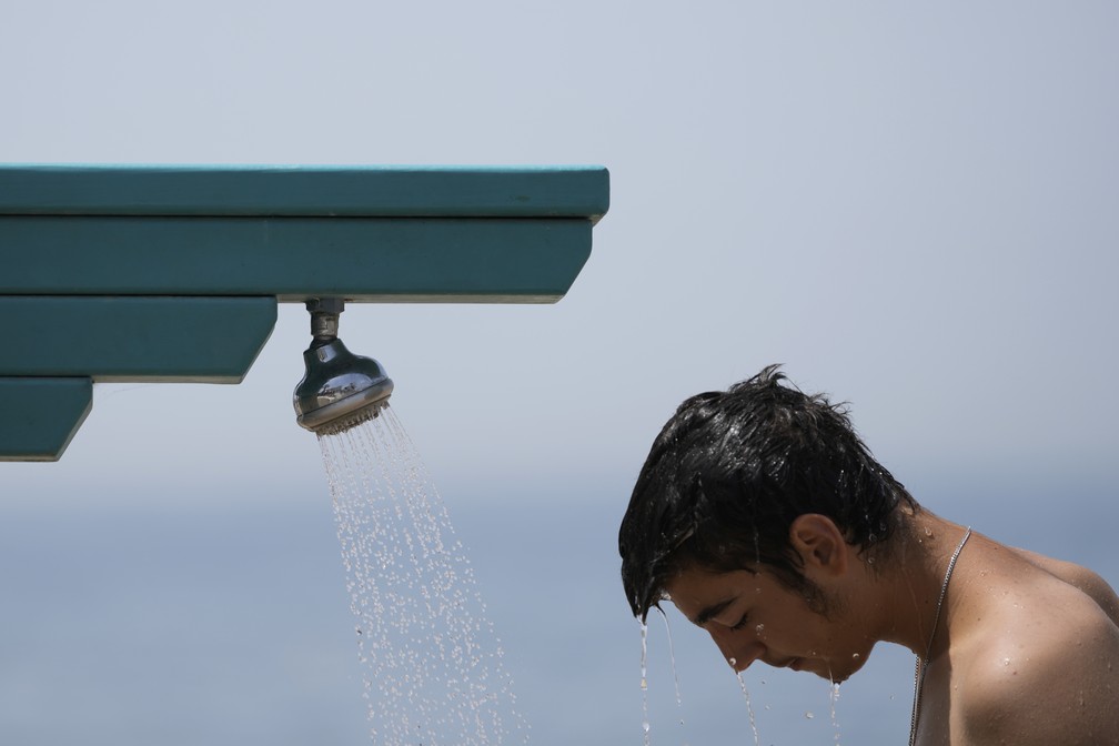 Um homem se banha em um chuveiro na praia pública de Paleo Faliro, no sul de Atenas, Grécia (23/06/22). — Foto: AP Photo/Thanassis Stavrakis