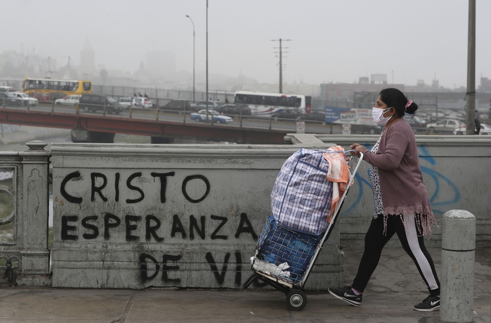 Uma vendedora ambulante passa por grafite com a mensagem em espanhol: 'Cristo, esperança para a vida' em Lima, no Peru, em julho de 2020 — Foto: Martin Mejia/AP