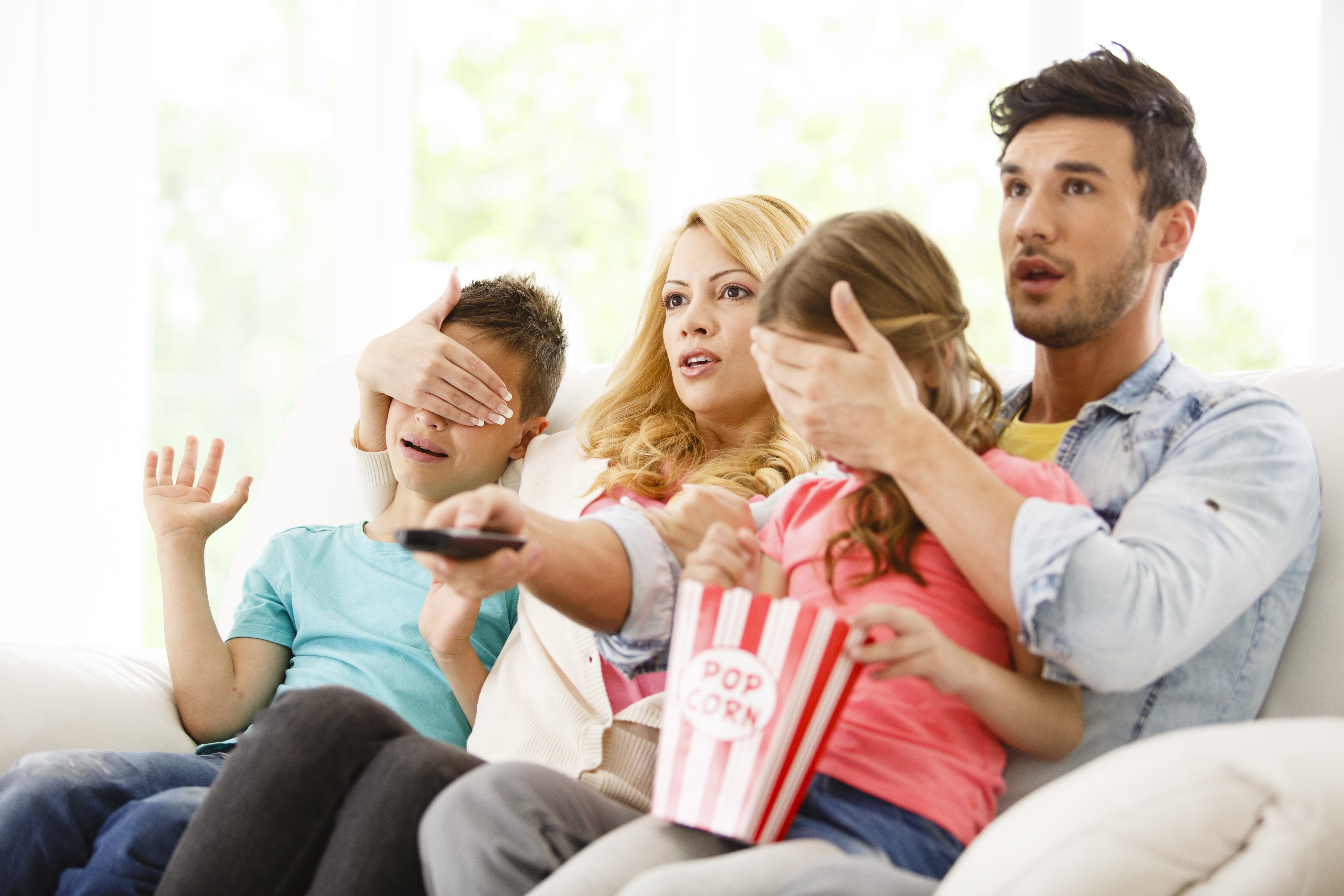 Mãe e pai tampando os olhos dos filhos enquanto assistem tv (Foto: Getty Images)