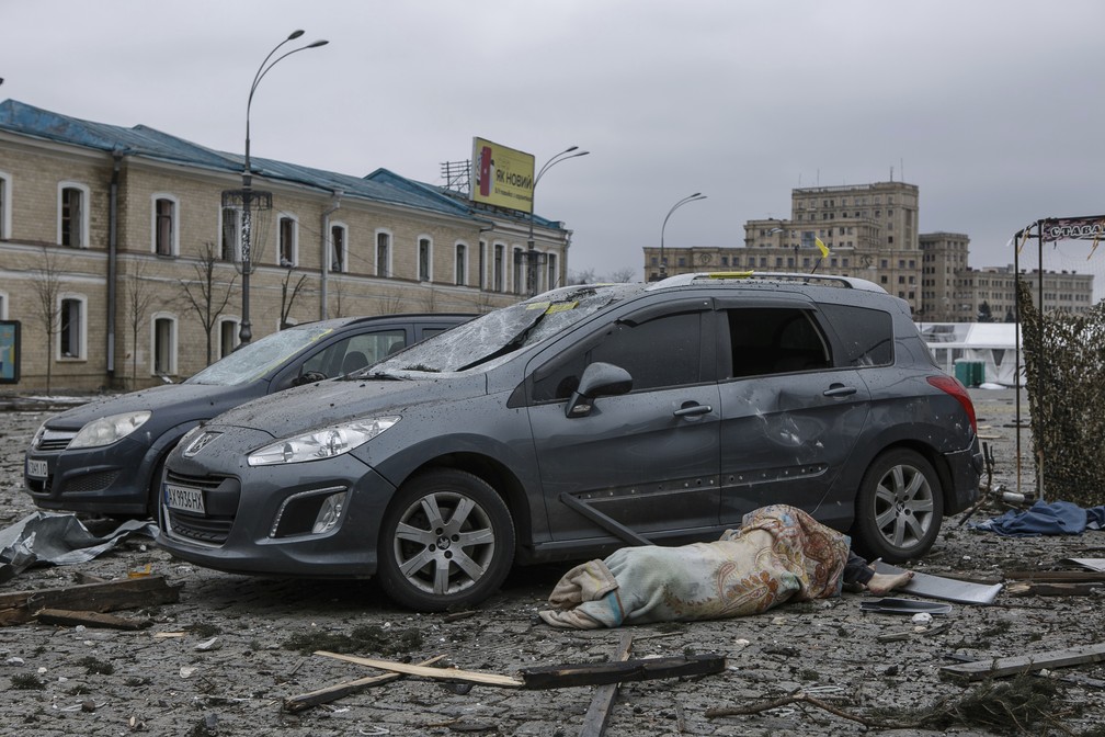 1º de março - Corpo de uma vítima é visto ao lado de carros danificados após o bombardeio do prédio da Prefeitura em Kharkiv, Ucrânia — Foto: Pavel Dorogoy/AP