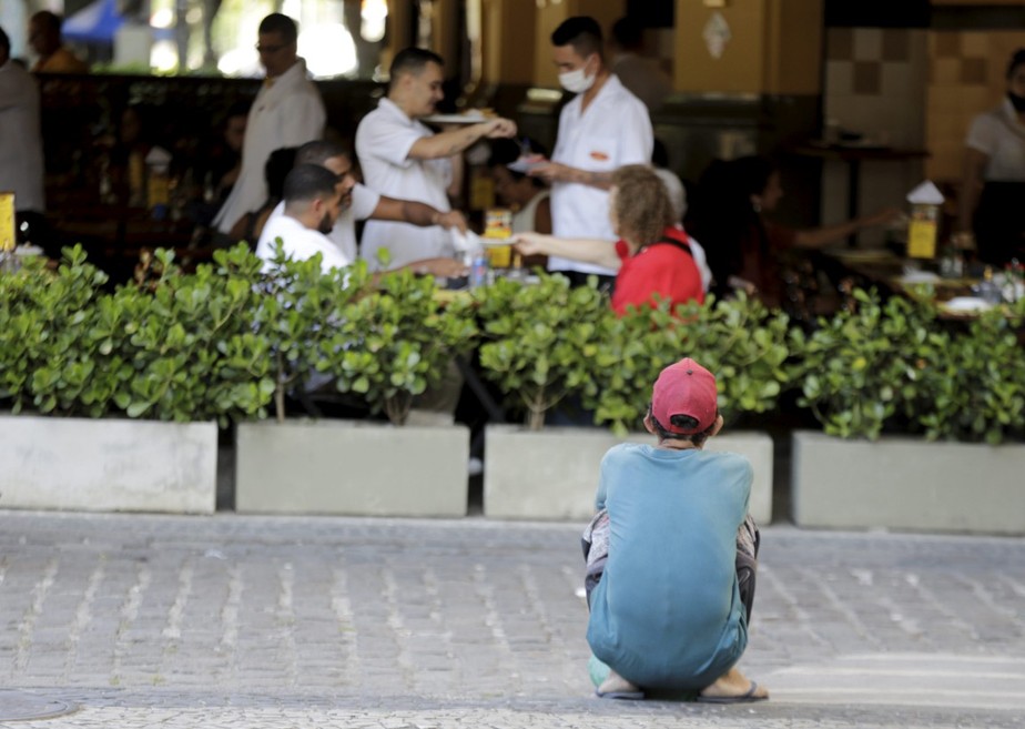 Morador de rua espera por restos de comida de um restaurante: o drama da fome