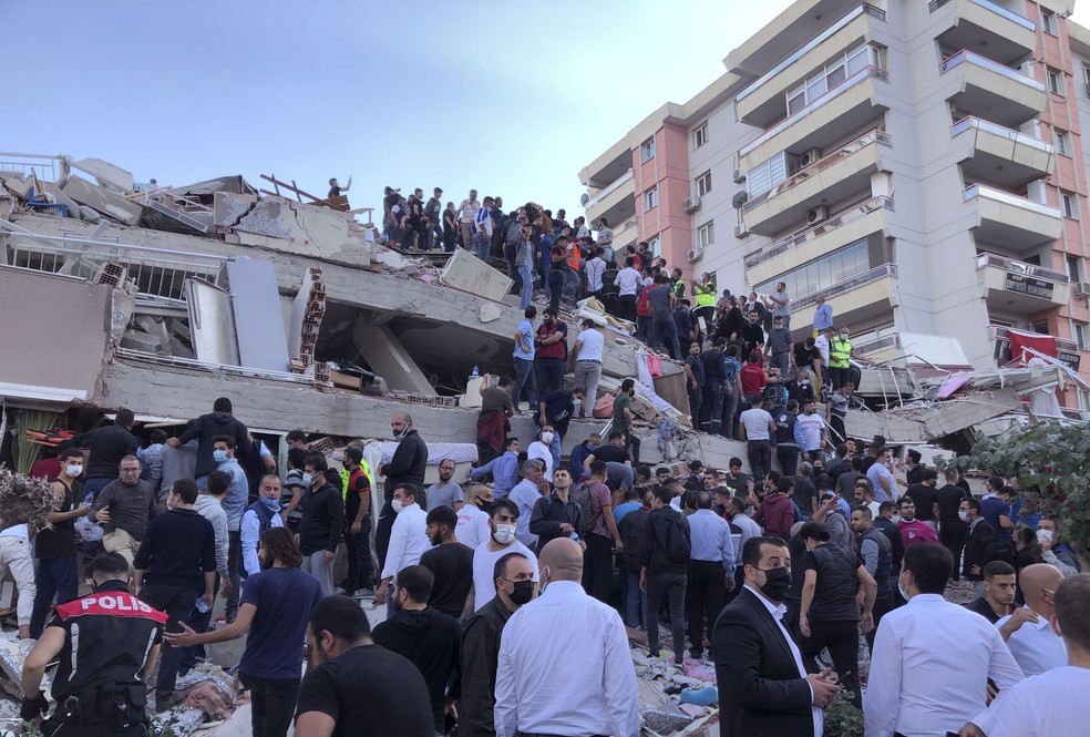 Trabalhadores do resgate tentam socorrer pessoas feridas nos escombros de um prédio que desabou na Turquia após um forte terremoto no Mar Egeu nesta sexta-feira (30)appe — Foto: Ismail Gokmen/AP