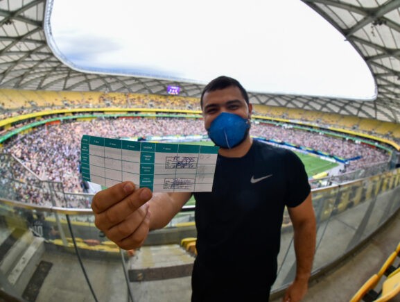 Torcedor exibe caderneta de vacinação em jogo realizado como evento-teste na Arena da Amazônia (Foto: Faar/Governo do Amazonas)