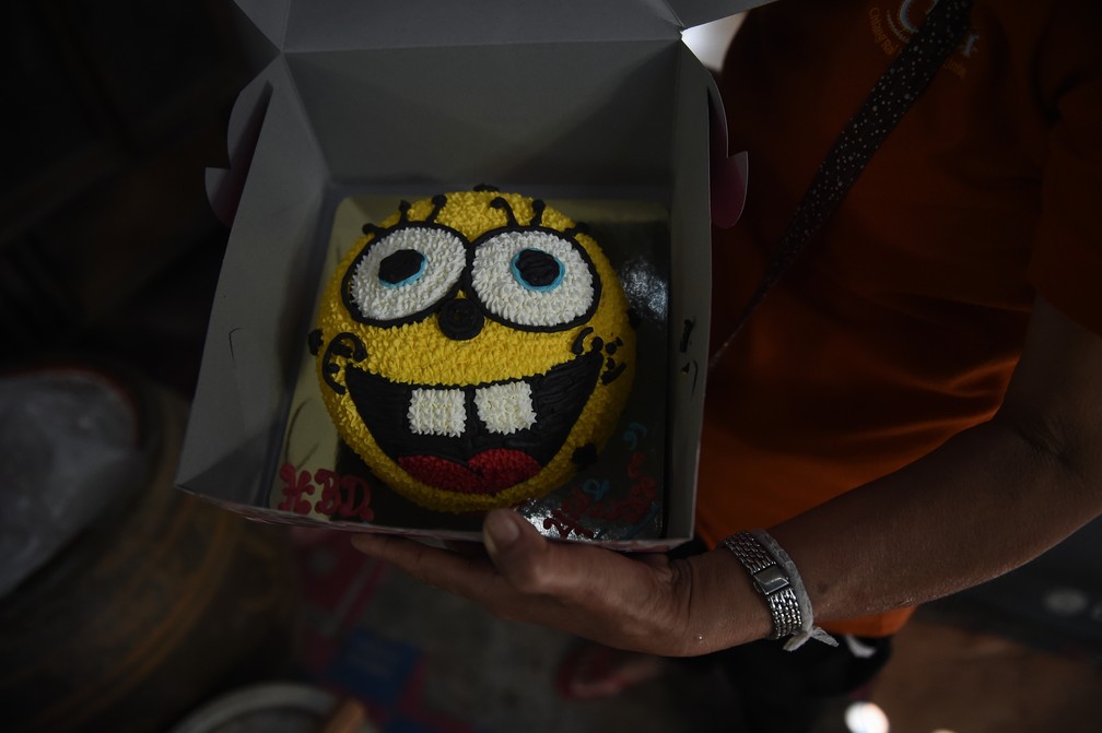 Mãe mostra o bolo de aniversário ainda guardado para rapaz preso em caverna na Tailândia (Foto: Lillian Suwanrumpha / AFP)