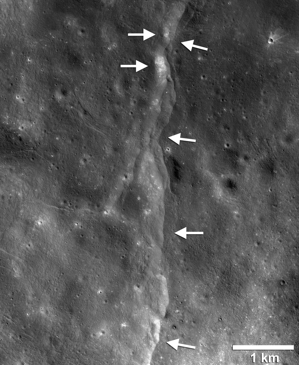  Esta proeminente escarpa de falha de impulso do lóbulo lunar é uma das milhares de imagens descobertas nas imagens Lunar Reconnaissance Orbiter Camera (LROC). A falha escarpada ou escarpada é como um degrau na paisagem lunar (setas brancas apontando para a esquerda) formadas quando a crosta próxima da superfície é empurrada, quebrada e empurrada para cima ao longo de uma falha quando a Lua se contrai. Campos de pedregulhos, trechos de solo relativamente alto e luminoso ou regolito, são encontrados na face escarpada e no terreno escarpado (lado alto da escarpa, setas apontando para a direita). Imagem LROC NAC quadro M190844037LR. — Foto: NASA/GSFC/Universidade Estadual do Arizona/Smithsonian