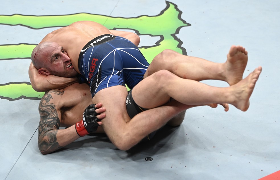 Alexander Volkanovski (por baixo) luta para sair da guilhotina de Brian Ortega (por cima) no UFC 266 — Foto: Getty Images