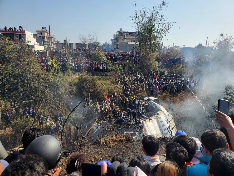 Uma visão geral das pessoas reunidas após a queda de um avião em Pokhara, Nepal, neste domingo (15) — Foto: Reuters