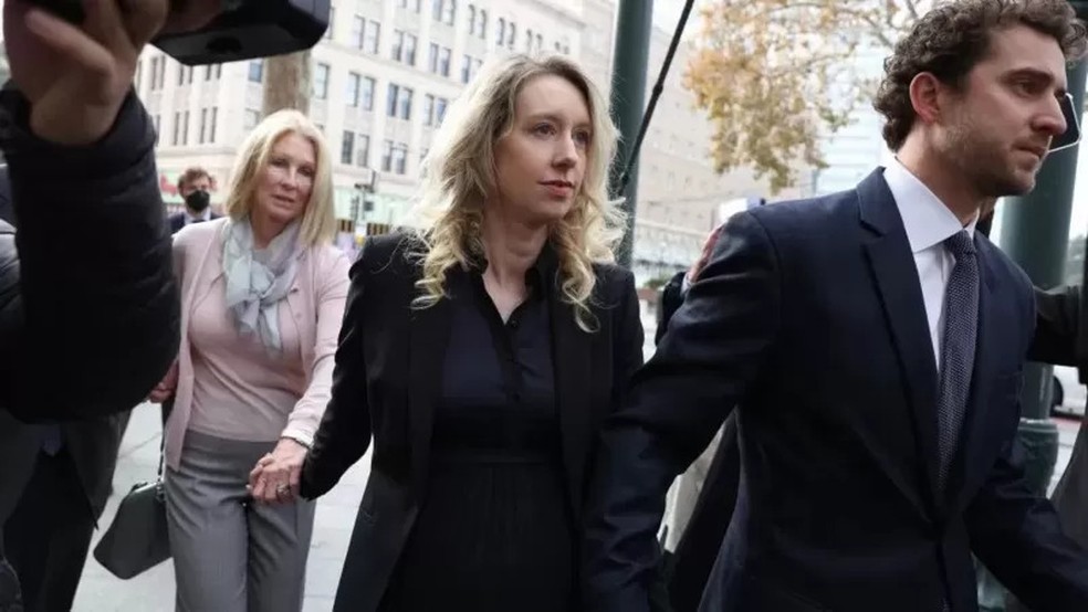 Holmes (no centro) junto com o marido e a mãe dela enquanto entravam no tribunal. — Foto: Getty Images
